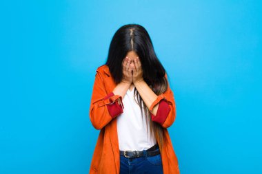 Genç, güzel Latin bir kadın üzgün, hayal kırıklığına uğramış, gergin ve depresif, yüzünü iki eliyle kaplayan, yassı duvara karşı ağlayan