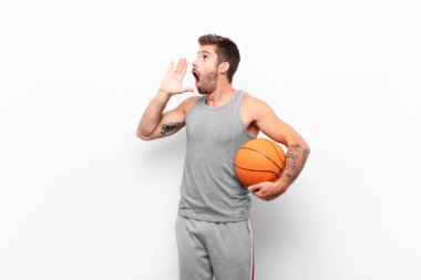 Genç yakışıklı adam öfkeyle ve yüksek sesle bağırarak kenardaki boşluğu kopyalasın, eli ağzının yanında basketbol topu tutsun..