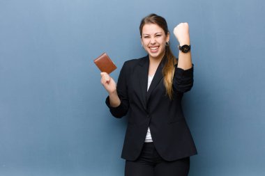 Cüzdanı grunge duvarına dayalı genç sarışın kadın.