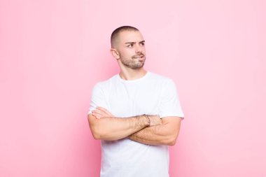 Genç yakışıklı adam şüphe ediyor ya da düşünüyor, dudağını ısırıyor ve kendini güvensiz ve gergin hissediyor, düz duvara karşı boşluğu kopyalamak istiyor.