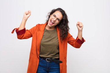 Genç ve güzel bir kadın kızgın bir ifadeyle ya da yumruklarıyla beyaz duvara karşı başarıyı kutlarken saldırganca bağırıyor.