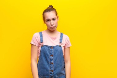 Genç sarışın güzel kız üzgün ve mızmız, mutsuz bir bakışla, olumsuz ve hayal kırıklığına uğramış bir tavırla sarı duvara karşı ağlıyor.