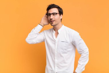 Genç yakışıklı bir adam gülümsüyor, tuhaf bir şekilde yan tarafa bakıyor, dedikoduları dinlemeye ya da bir sırrı duymaya çalışıyor.