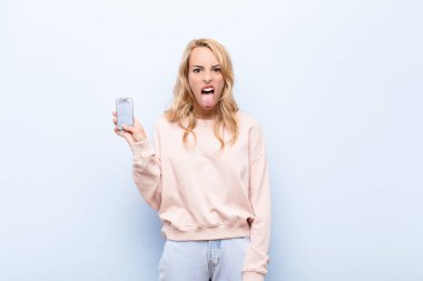 Genç sarışın kadın iğrenmiş ve rahatsız olmuş hissediyor. Dilini dışarı çıkarıyor. Pis ve iğrenç bir şeyden hoşlanmıyor.