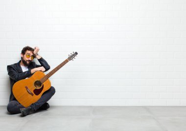 Gitarlı genç adam odada yerde yatıyor.