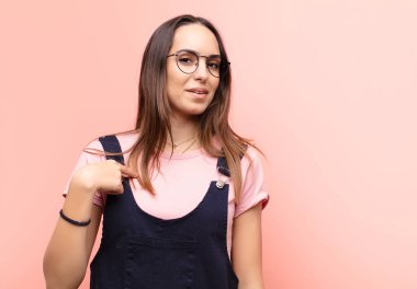 Kafası karışmış, kafası karışmış ve kendine güveni olmayan genç güzel bir kadın kendini gösterip kim olduğumu soruyor, ben mi? Pembe duvara yaslan