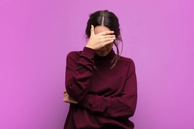 Genç, güzel bir kadın stresli, utanmış ya da üzgün görünüyor. Başı ağrıyor, yüzü mor duvara değiyor.