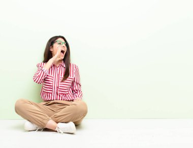 Genç ve güzel bir kadın öfkeyle bağırıyor. Yan taraftaki boşluğu kopyalamak için. Elleri ağızlarının yanında yerde oturuyor.
