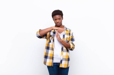 Genç, güzel, siyahi bir kadın ciddi, sert, kızgın ve canı sıkkın görünüyor.