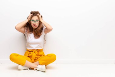 Genç sarışın kadın hayal kırıklığına uğramış ve sıkılmış hissediyor, başarısızlıktan bıkmış ve bıkmış, sıkıcı işlerden bıkmış, yerde oturuyor.