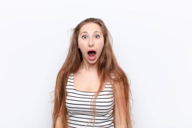 Genç sarışın kadın korkmuş ve şok olmuş hissediyor, ağzı açık beyaz duvara karşı şaşkınlık içinde.