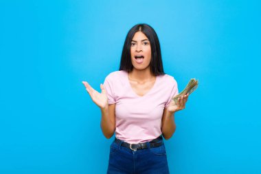 Genç, güzel Latin bir kadın mutlu, heyecanlı, şaşırmış ya da şok olmuş hissediyor, gülümsüyor ve şaşırıyor.