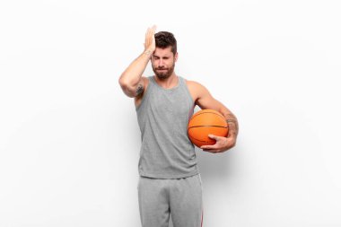 Genç ve yakışıklı bir adam stresli ve endişeli, depresyonda ve hayal kırıklığına uğramış, iki elini de bir basketbol topunu tutarak havaya kaldırıyor..