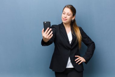 Genç sarışın kadın akıllı telefonu arka planda grunge duvarına karşı kullanıyor.