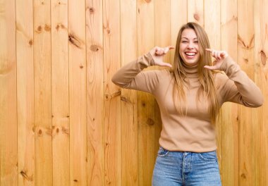 Genç sarışın kadın kendi gülüşünü çiziyor, iki eliyle, pozitif ve mutlu görünüyor, sağIık kavramı.