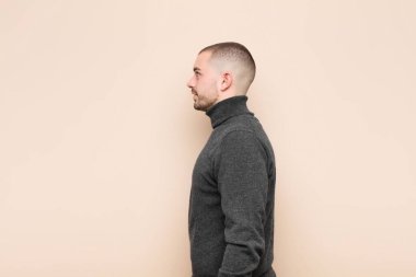 Profil görünümlü genç bir adam uzayı kopyalamaya çalışıyor, düşünüyor, hayal ediyor ya da düz duvara karşı hayal kuruyor.