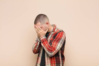 Genç yakışıklı adam, üzgün, hayal kırıklığına uğramış bakışlarıyla gözlerini kapatıyor. Ağlıyor, duvara yan bakıyor.