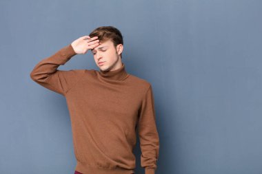 Genç sarışın adam stresli, yorgun ve hayal kırıklığına uğramış, alnından ter damlayan, umutsuz ve bitkin hisseden, düz duvara yaslanmış.