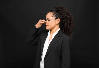 Genç siyahi kadın iğreniyor, pis ve tatsız bir kokunun kokusunu almaktan kaçınmak için burnunu tutuyor.