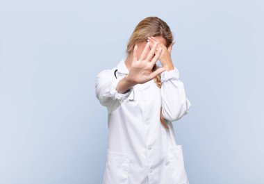 Genç, güzel, Latin bir kadın yüzünü eliyle kapatıyor ve kamerayı durdurmak için diğer elini öne koyuyor. Fotoğraf ya da resimleri reddediyor. doktor konsepti