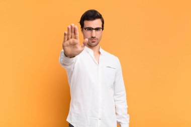 Adam ciddi, sert, hoşnutsuz ve kızgın görünüyor. Avuç içini açıp jesti durduruyor.