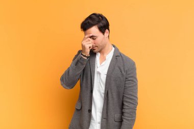 Genç yakışıklı, stresli, mutsuz ve hayal kırıklığına uğramış, alınlı ve şiddetli baş ağrısı çeken bir adam.