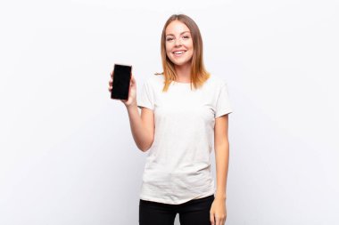 Kızıl saçlı, güzel bir kadın mutlu ve hoş bir şekilde şaşırmış görünüyor. Elinde akıllı bir telefon tutarak büyülenmiş ve şok olmuş bir ifadeyle heyecanlanıyor.