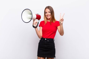 Kızıl saçlı güzel bir kadın gülümsüyor ve arkadaş canlısı görünüyor, iki ya da iki numarayı gösteriyor, elinde bir megafonla geriye doğru sayıyor.