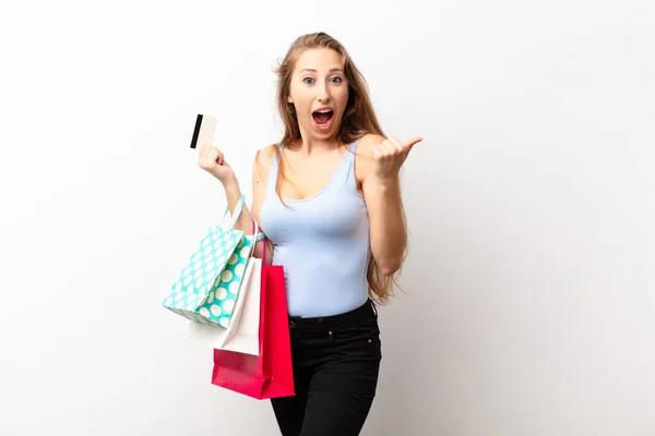 若い金髪の女がショックを受けて興奮して幸せ笑って成功を祝うなんてショッピングバッグ — ストック写真