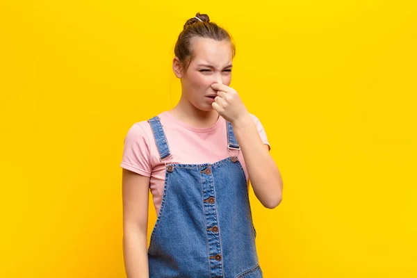 若いブロンドの可愛い女の子はうんざりして鼻をつつく黄色の壁に対して汚くて不快な悪臭を避けるために — ストック写真