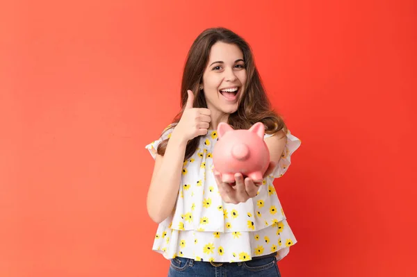 Jovem Mulher Bonita Contra Parede Vermelha Segurando Piggybank — Fotografia de Stock