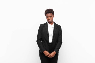 Genç ve güzel siyah kadın üzgün ve mızmız, mutsuz bir bakışla ağlayan, olumsuz ve hayal kırıklığına uğramış bir tavırla beyaz duvara karşı.