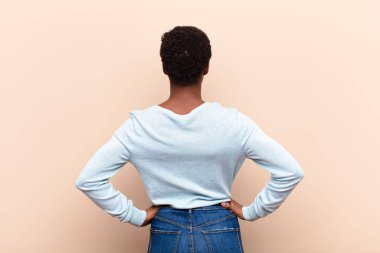 Genç, siyah bir kadının kafası karışmış ya da dolu ya da şüphe ve soru dolu, merak içinde, elleri kalçasında, dikiz aynasından.