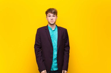 Genç, sarışın bir adam üzgün ve stresli. Kötü bir sürpriz yüzünden üzgün. Olumsuz, kaygılı bir bakışla düz duvara yaslanmış.