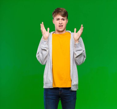 Genç sarışın adam ellerini havaya kaldırarak bağırıyor. Öfkeli, sinirli, stresli ve krom anahtar duvara karşı üzgün hissediyor.