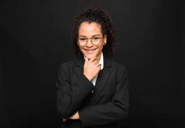 Genç siyah kadın gülümsüyor, hayattan zevk alıyor, mutlu, arkadaş canlısı, tatmin olmuş ve tasasız.