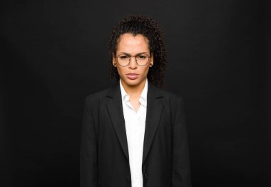 Genç siyah kadın üzgün ve stresli hissediyor, kötü bir sürpriz yüzünden üzgün, olumsuz, endişeli bir bakışla siyah duvara bakıyor.