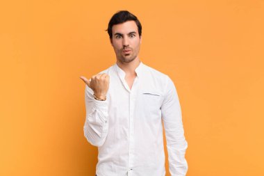 Genç ve yakışıklı adam inançsızlıktan şaşkın şaşkın bakıyor, yan taraftaki objeyi işaret ediyor ve diyor ki vay canına, inanılmaz.