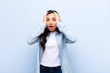 Genç Latin güzel bir kadın dehşete kapılmış ve şok olmuş hissediyor, el ele tutuşuyor ve düz duvara karşı yapılan bir hata karşısında panikliyor.