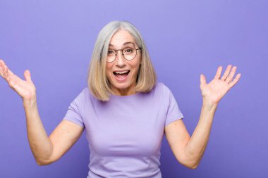 Yaşlı ya da orta yaşlı güzel bir kadın kendini mutlu, şaşkın, şanslı ve şaşırmış hissediyor. Zaferi iki eli havada kutluyor.