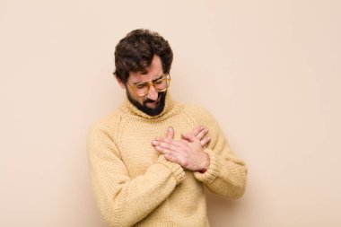 Genç havalı adam üzgün, incinmiş ve kalbi kırık görünüyor, iki elini de kalbe yakın tutuyor, ağlıyor ve yassı duvara karşı depresyona giriyor.