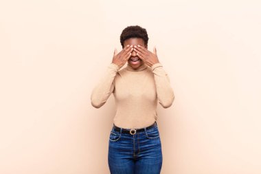 Genç ve güzel siyah kadın gülümsüyor ve mutlu hissediyor, iki eliyle gözlerini kapatıyor ve inanılmaz bir sürpriz bekliyor.