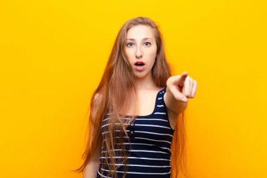 Genç sarışın kadın şaşkın ve şaşırmış hissediyor, hayranlıkla yukarı bakıyor, şaşırmış, ağzı açık bakıyor.