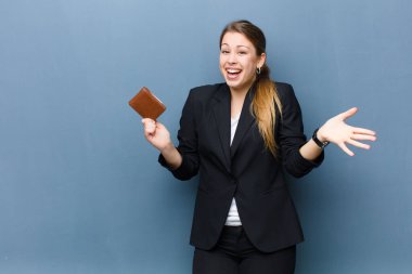 Cüzdanı grunge duvarına dayalı genç sarışın kadın.