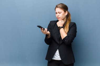 Genç sarışın kadın akıllı telefonu arka planda grunge duvarına karşı kullanıyor.