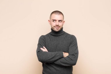 Genç yakışıklı adam şüphe ediyor ya da düşünüyor, dudağını ısırıyor ve kendini güvensiz ve gergin hissediyor, düz duvara karşı boşluğu kopyalamak istiyor.