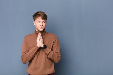 Genç sarışın adam gururlu, yaramaz ve kibirli hissederken şeytani bir plan kuruyor ya da düz duvara karşı izole edilmiş bir numara düşünüyor.