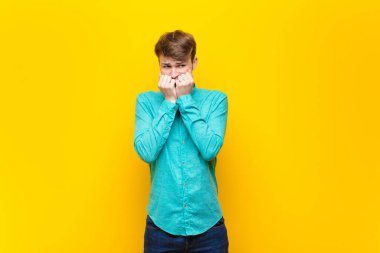 Genç sarışın adam endişeli, gergin, stresli ve korkmuş görünüyor. Tırnaklarını yiyor ve düz duvara yaslanmış bir fotokopi odası arıyor.