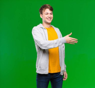 Genç sarışın adam gülümsüyor, seni selamlıyor ve başarılı bir anlaşma için el sıkışma teklif ediyor, kroma anahtarına karşı işbirliği konsepti