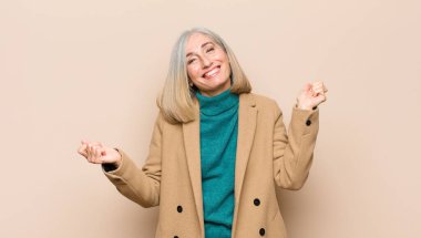 Yaşlı ya da orta yaşlı güzel bir kadın gülümsüyor, kaygısız, rahat ve mutlu hissediyor, dans ediyor ve müzik dinliyor, partide eğleniyor.